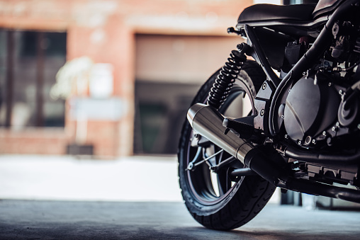 Cropped image of modern black motorcycle in garage. Cafe racer.
