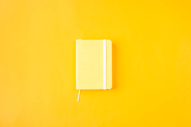 istock Yellow minimalistic notepad for entries on a yellow background. Planning, keeping a diary, time management concept. Top view, flat lay 996761770