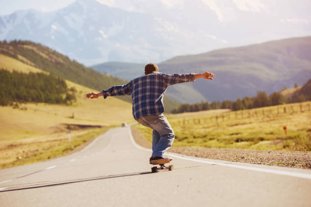 Man skating or longboarding at straight mountain road