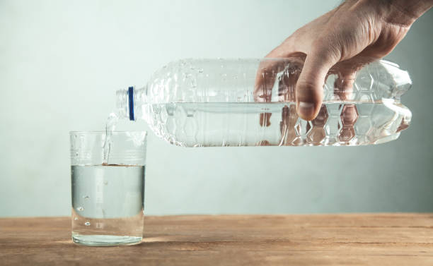 istock Man hand pours clean water from a bottle into a glass. 996769190