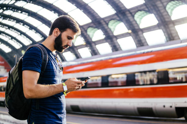 istock Beautiful young man looking at the phone while waiting for the train 996773228
