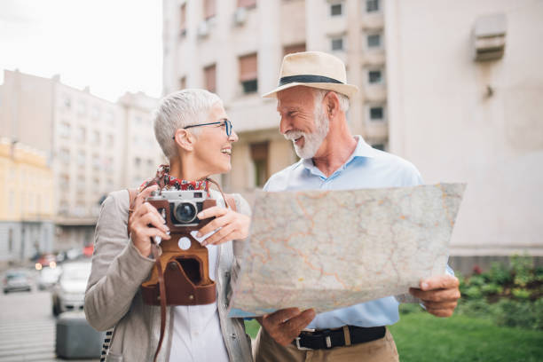 istock Mature woman with camera and man holding a map looking at each other 996773914