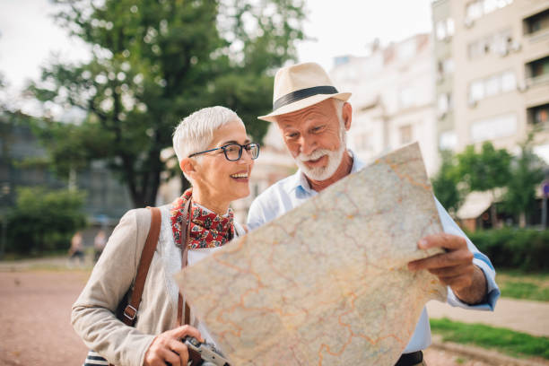 istock Older man showing direction on the map to a woman standing beside him 996776016