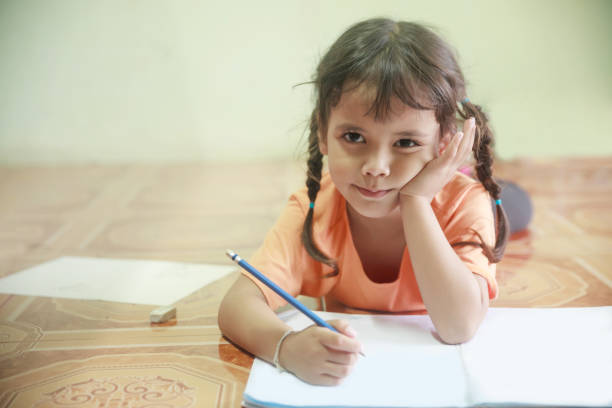 istock little girl writing something on paper. 996793214
