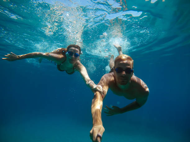 istock Cheerful couple having fun underwater and making selfie. 996796516
