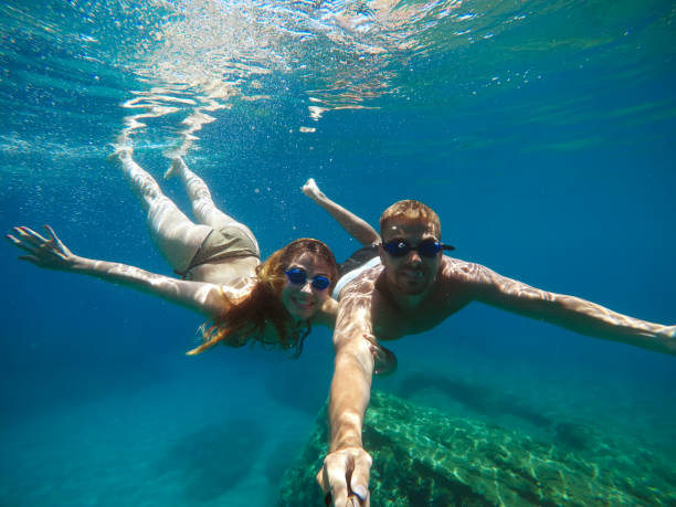 istock Cheerful couple having fun underwater and making selfie. 996796550