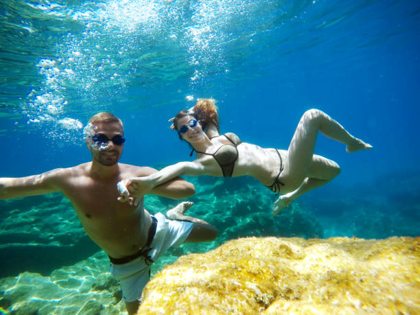istock Cheerful couple having fun underwater and making selfie. 996796620