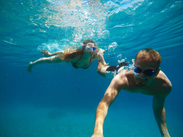 istock Cheerful couple having fun underwater and making selfie. 996796958
