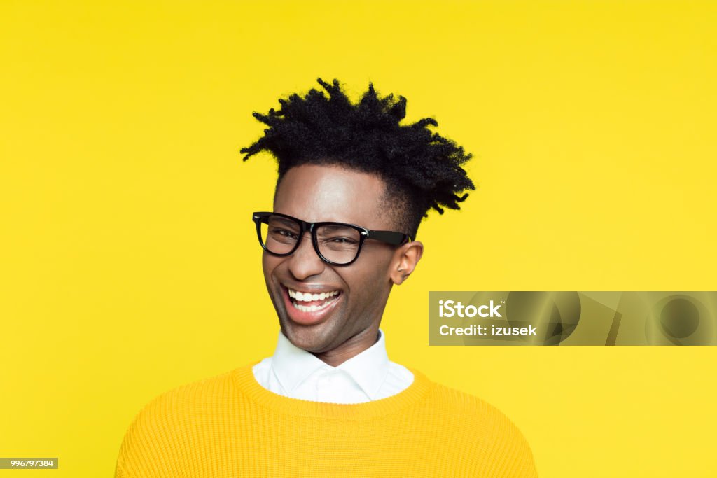 Yellow portrait of nerdy young man making funny face Funny portrait of nerdy young afro American man wearing yellow sweater laughing at the camera. Cheesy Grin Stock Photo