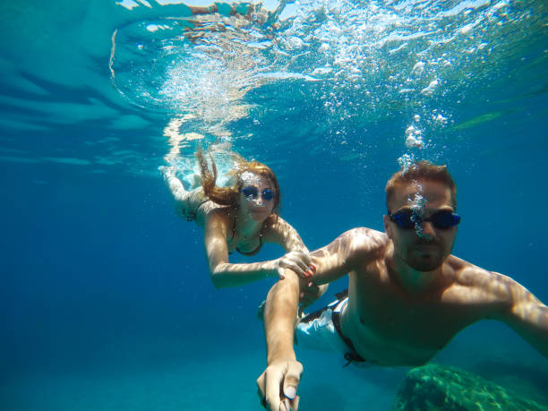 istock Cheerful couple having fun underwater and making selfie. 996797908