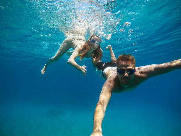 istock Cheerful couple having fun underwater and making selfie. 996797936