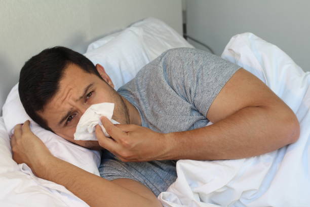 istock Man blowing his nose in bed 996800294