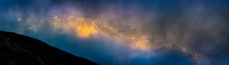 Warm light of daybreak illuminating the sawtooth ridge of Nuptse and summit spire of Lhotse deep in the remote Himalaya mountain wilderness of the Everest National Park, a UNESCO World Heritage Site, Nepal.
