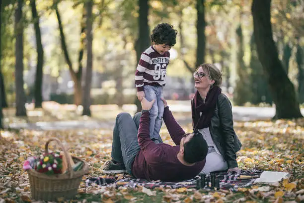 Happy family having picnic in the park on a sunny autumn day