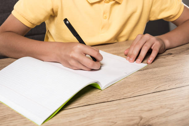 istock cropped image of schoolboy doing homework in empty textbook at table 996807706