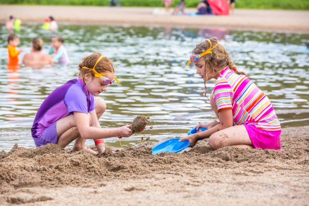 istock Two Young Girls Digging in Sand at Edge of Beach 996813084