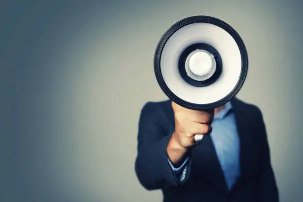 Photo of businessman with megaphone in hand in front of face