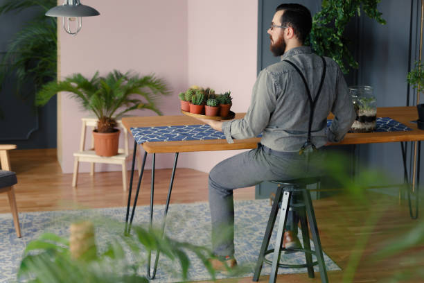 istock Hipster with beard holding plate with succulents in modern interior with plants 996829094