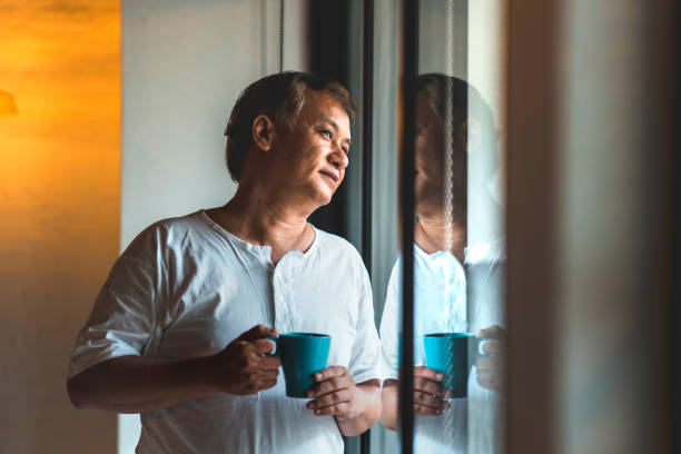 istock Senior man drinking coffee and looking outside the window 996832436
