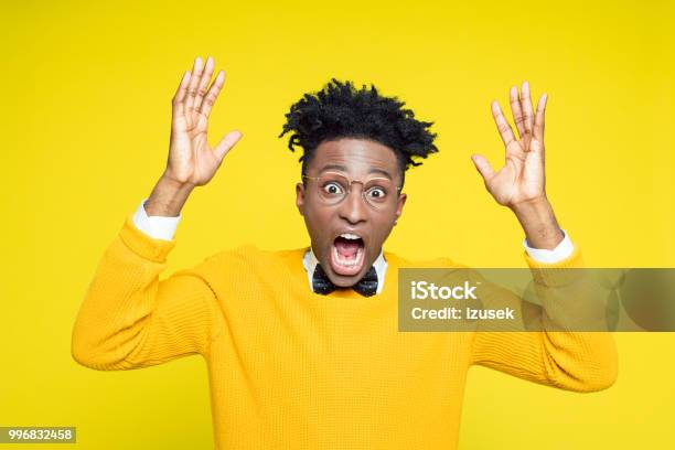 Portrait Of Angry Nerdy Young Man Gesturing Against Yellow Background Stock Photo - Download Image Now