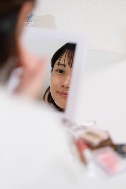 istock woman putting concealer on face 996835736