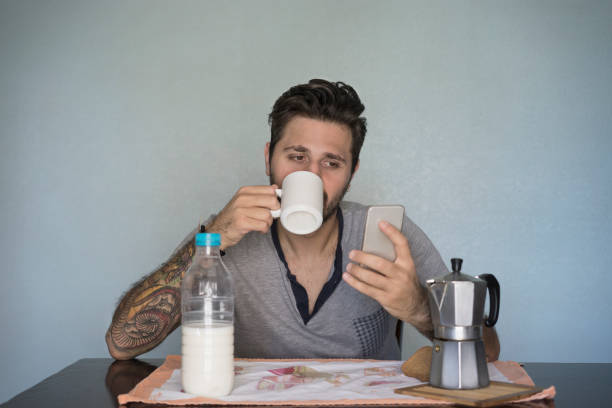 istock Young Man Do Breakfast while check his phone and Drink coffee 996836214