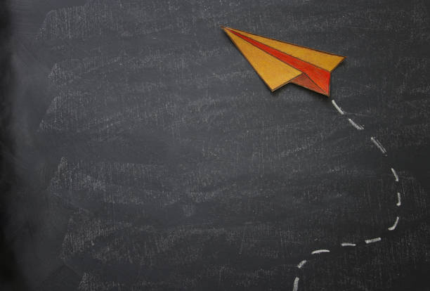 istock Top view image of paper plane over classroom blackboard background. 996836320