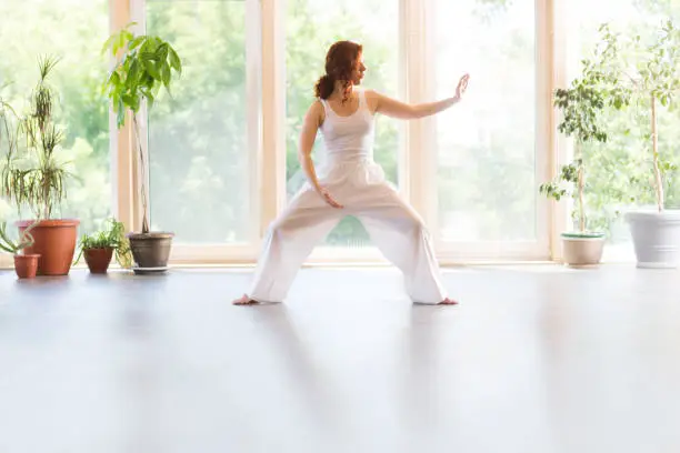 Photo of Young Woman praticing tai chi chuan in the gym. Chinese management skill Qi's energy.