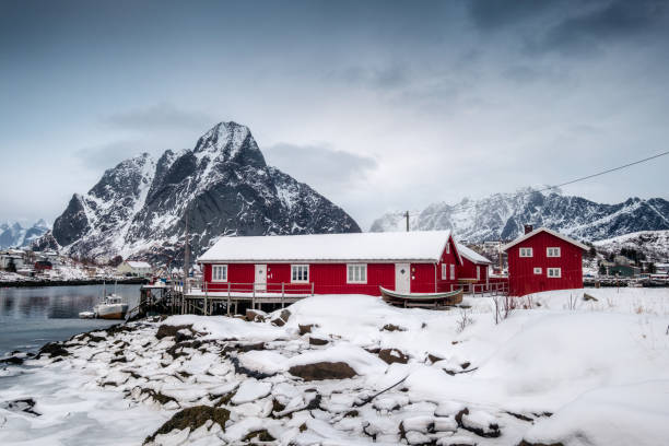 istock Snowfall on red house with harbor in valley on arctic ocean 996839754