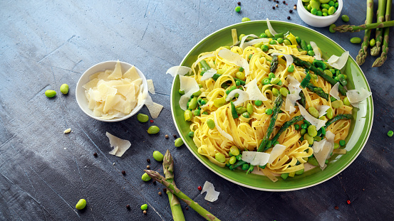 Pasta tagliatelle with asparagus, peas, beans and parmesan cheese on top. healthy food.