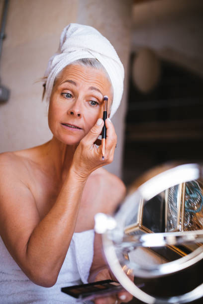 istock Beautiful senior woman putting on make-up and applying eyeshadow 996851714