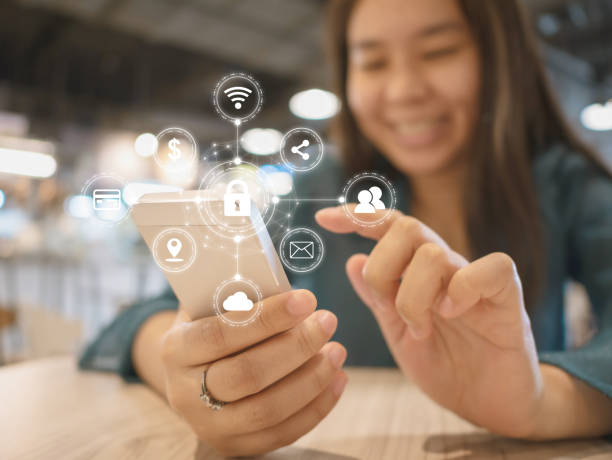 istock Young woman smiling and using smartphone and with icon graphic symbol cyber security network protection of connection devices and secure personal data in mobile phones 996865396
