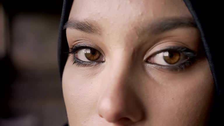 Close portrait of young muslim woman's eyes looking at camera in hijab, sad and depressed expression