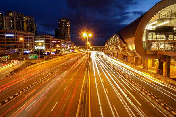 istock Light Trails On Road By Illuminated Buildings Against Sky At Night 996872324