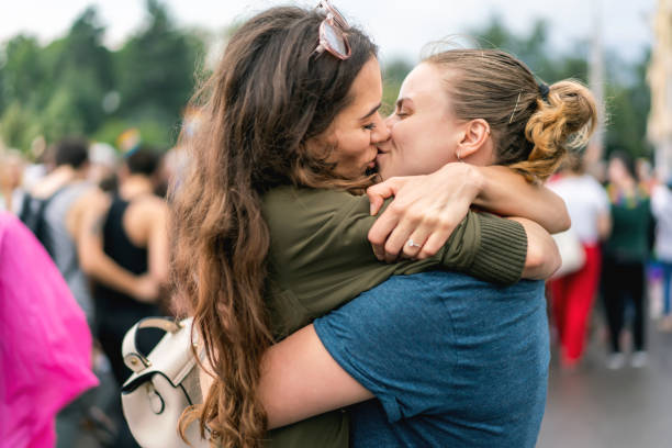 Young adult female couple  at pride parade Young adult female couple  at pride parade kissing stock pictures, royalty-free photos & images