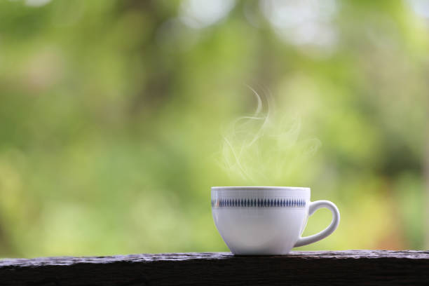 istock White coffee mug on wooden floor and green nature background. 996884190