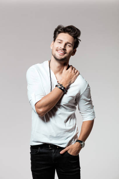 Portrait of attractive young man standing over grey background and smiling