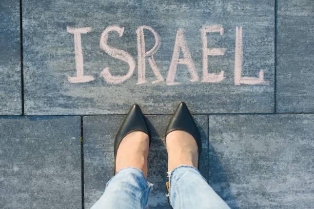 istock View from above, female feet with text Israel written on grey sidewalk. 996904622
