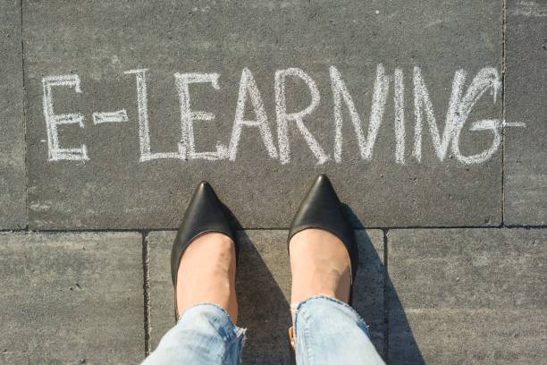 istock View from above, female feet with text e-learning written on grey sidewalk. 996916024