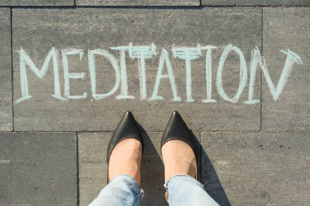 istock View from above, female feet with text meditation written on grey sidewalk. 996916582