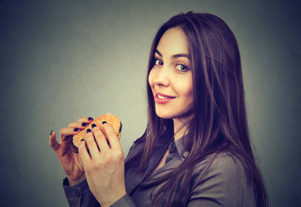 istock Cute woman with a cheeseburger looking at camera 996928134