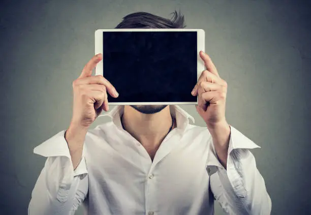 Photo of Anonymous man covering face with tablet computer