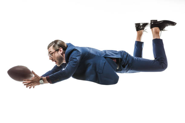 side view of businessman catching rugby ball while falling isolated on white