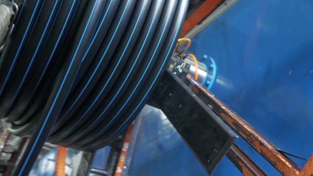istock Roll threading coil pipe. Manufacture of plastic water pipes factory. Process of making plastic tubes on the machine tool with the use of water and air pressure. 996939952