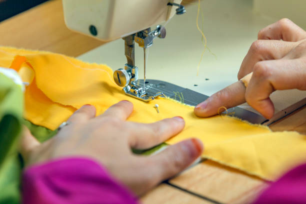 Woman sewing with sewing machine in sewing course, Turkey. Sewing at textile workshop. Sewing is the craft of fastening or attaching objects using stitches made with a needle and thread.