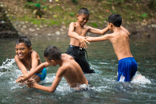 A close-up of a happy young boy playing and splashing in the shallow water of the river, radiating energy and carefree joy.