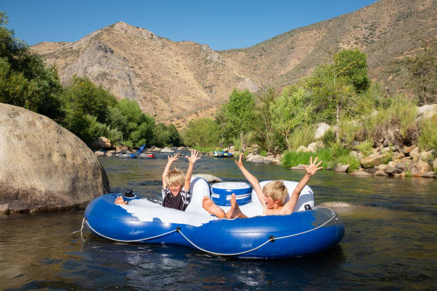 istock Two Kids On A Tube Floating Down A River in The Mountains 996958726