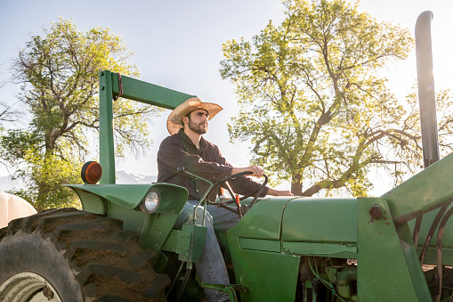 Young cowboy farmer driving tractor