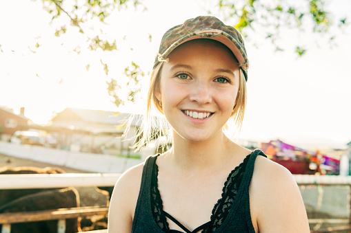 Headshot portrait of teenage American girl outdoors wearing baseball cap