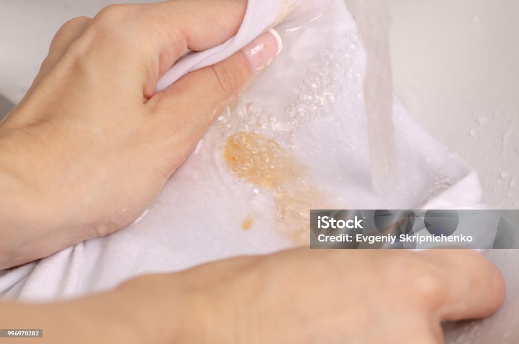 Laver une tache sur les vêtements blancs sous tache d’eau - Photo de Taché libre de droits